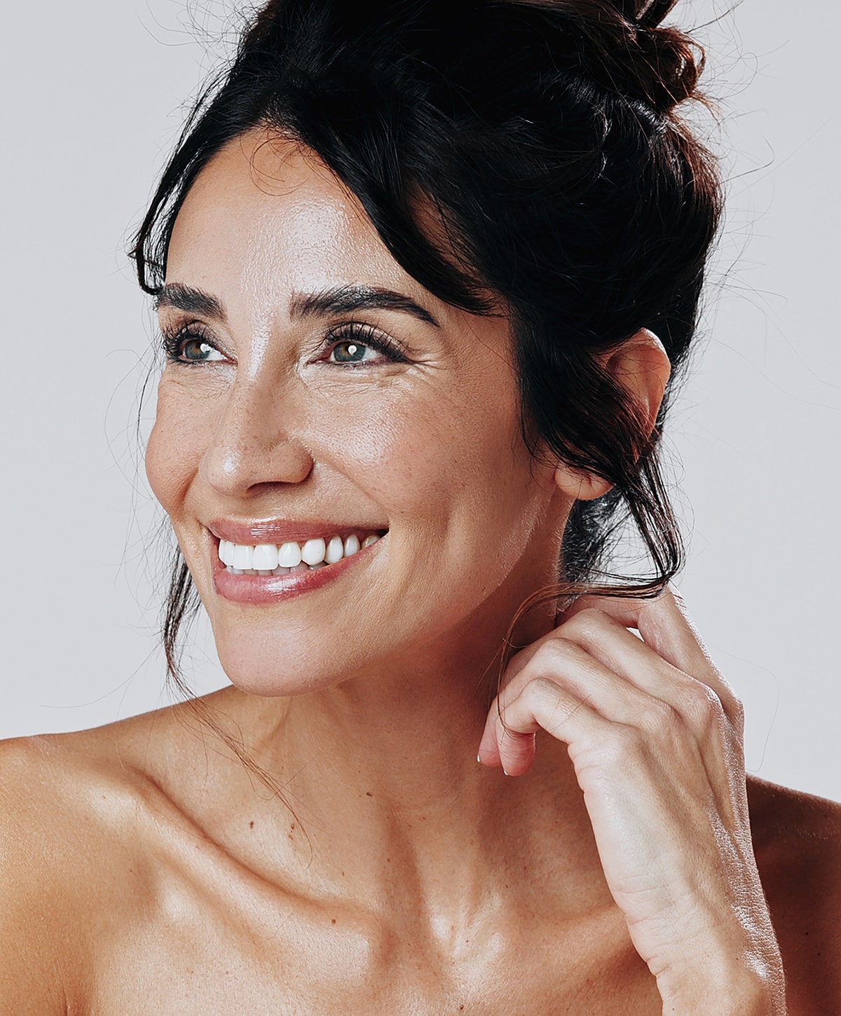 Smiling woman with radiant skin and elegant hairstyle.