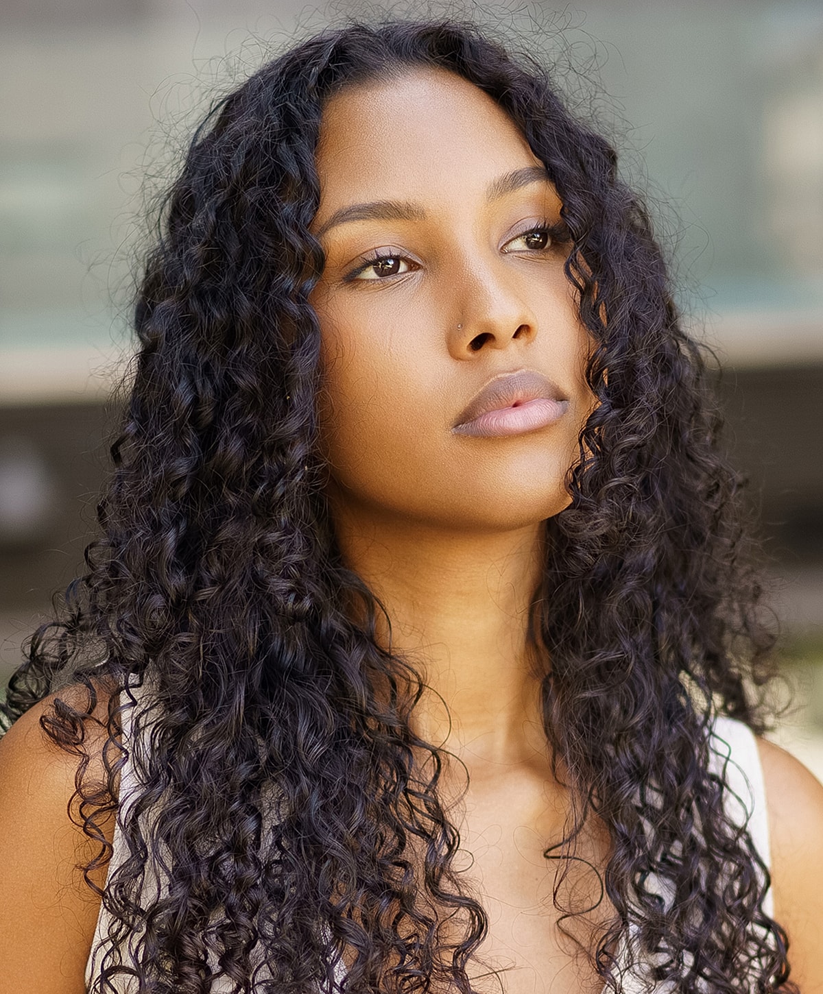 Woman with curly hair looking thoughtfully upwards.