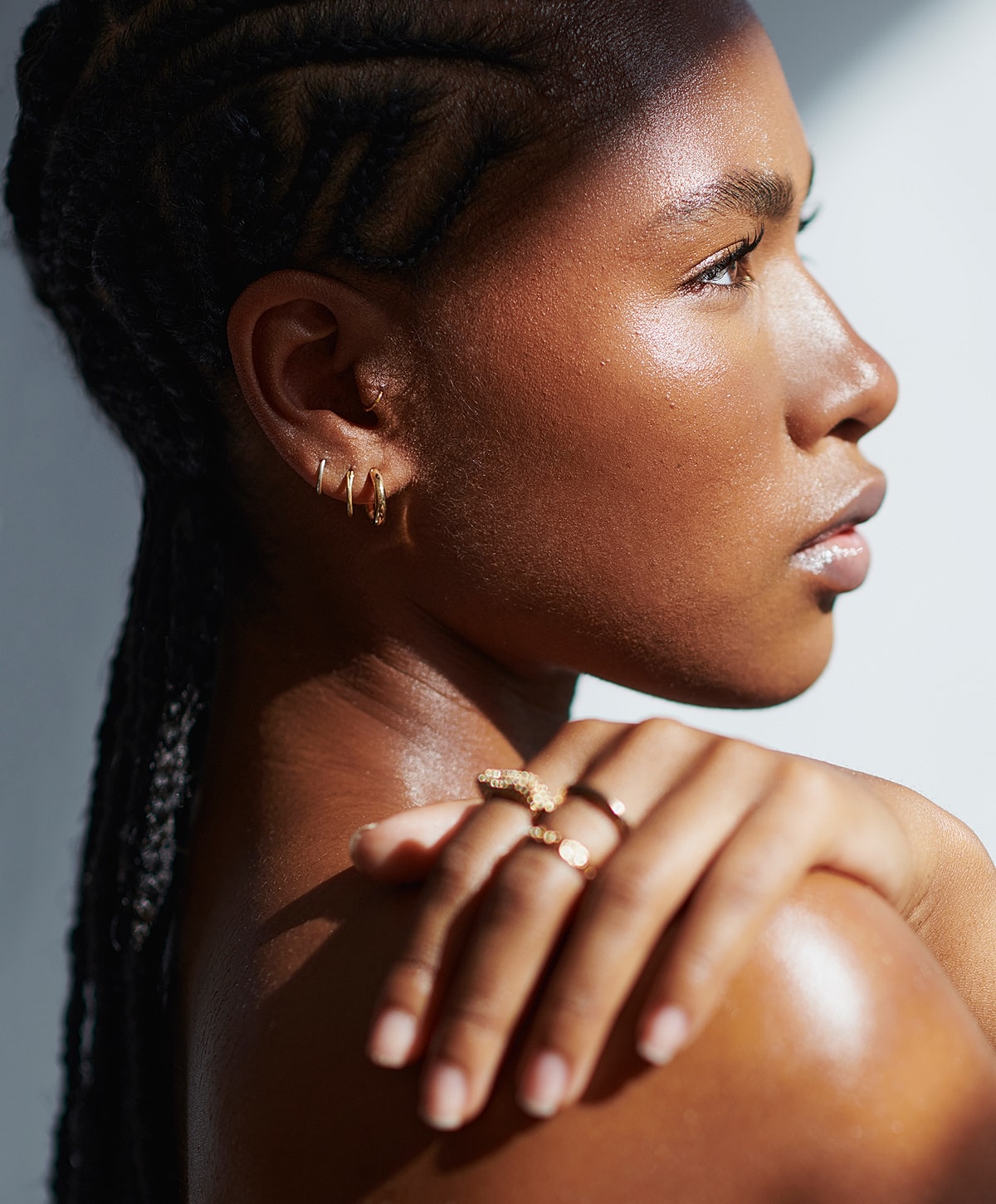 Model showcasing gold jewelry and braided hairstyle.