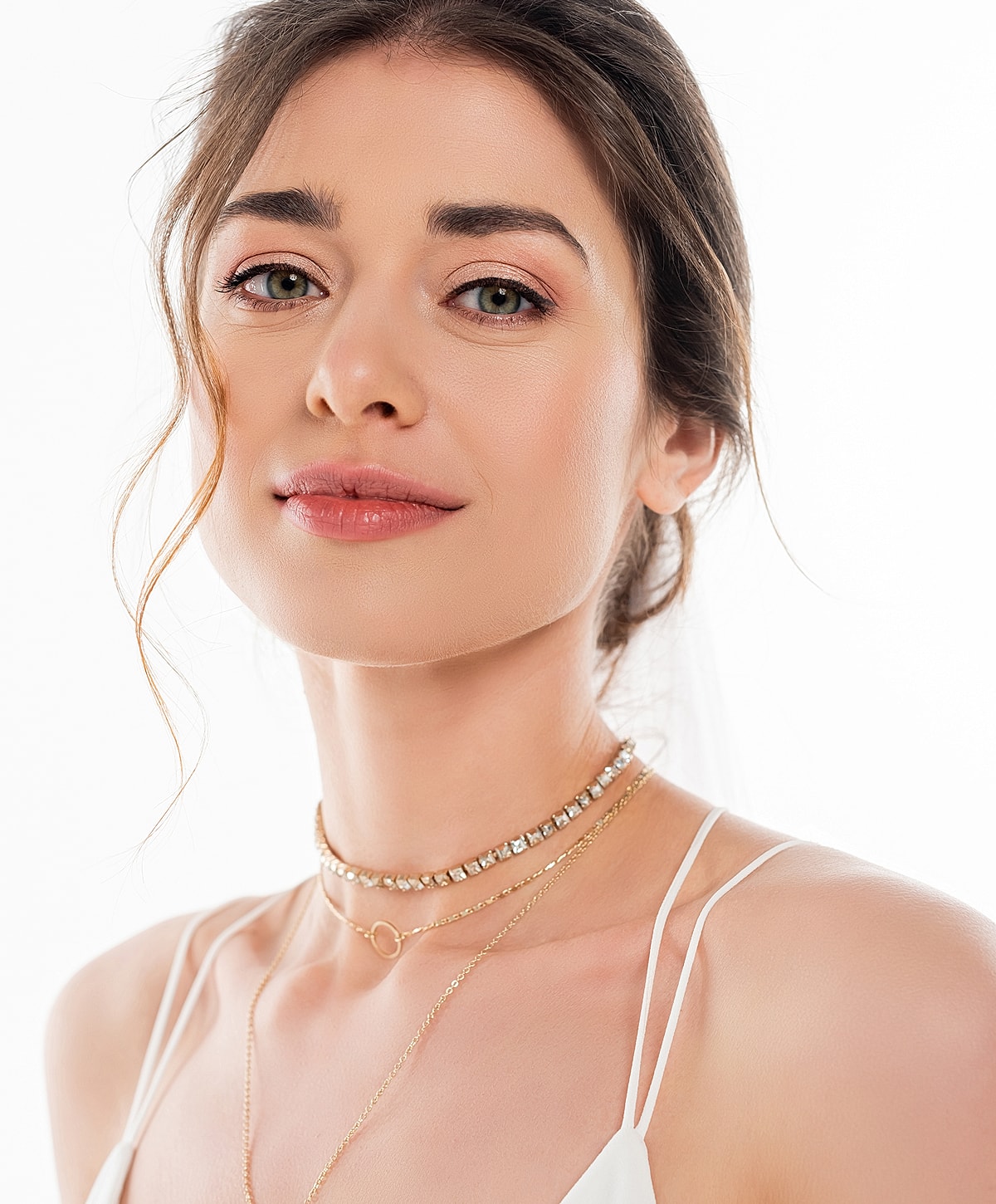 Smiling woman with layered necklaces, natural makeup.
