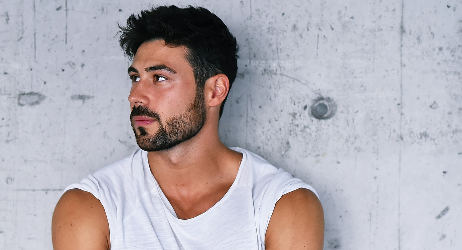 Man looking thoughtfully against a concrete wall.