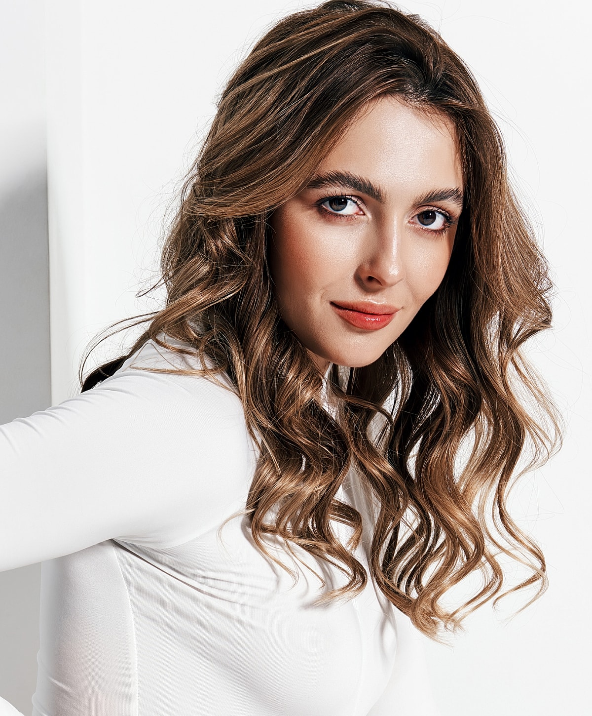 Woman with wavy hair in a white outfit.