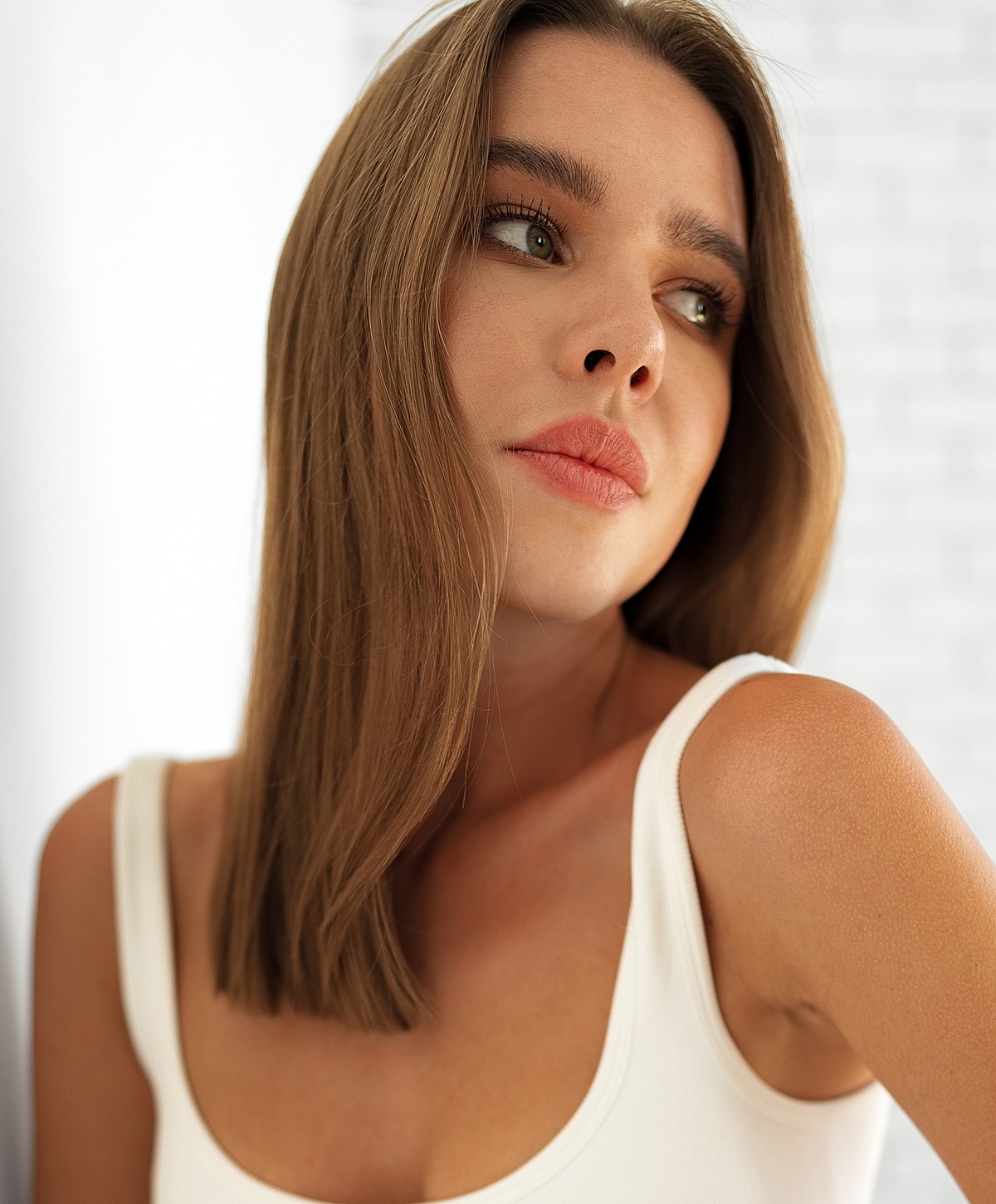 Woman with long hair in a white tank top.