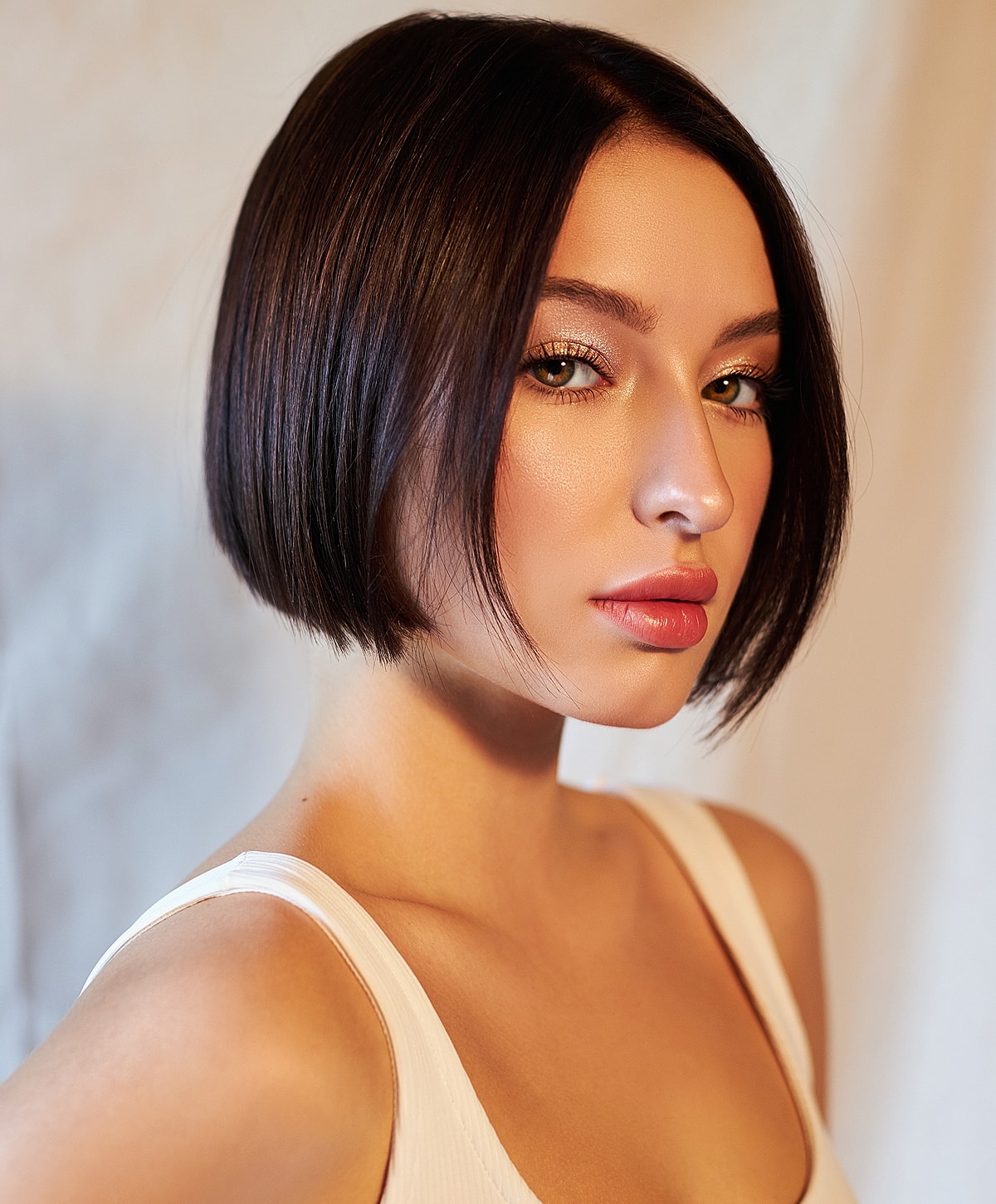 Young woman with sleek bob hairstyle and makeup.