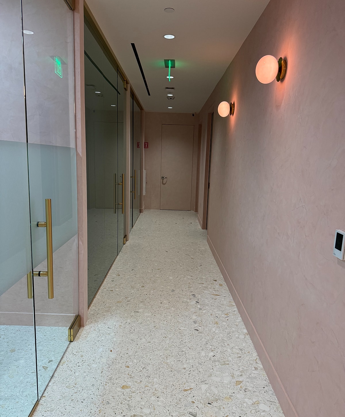 Modern hallway with glass doors and stylish lighting.