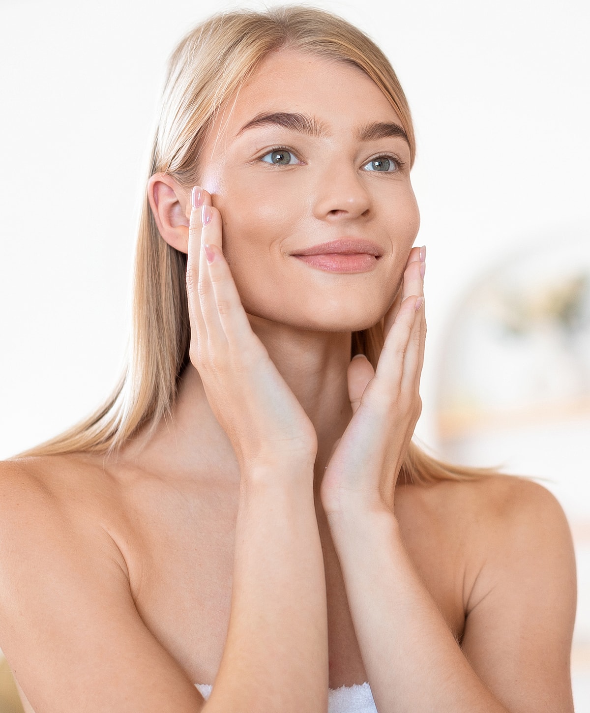 Woman applying skincare, smiling, with healthy skin.
